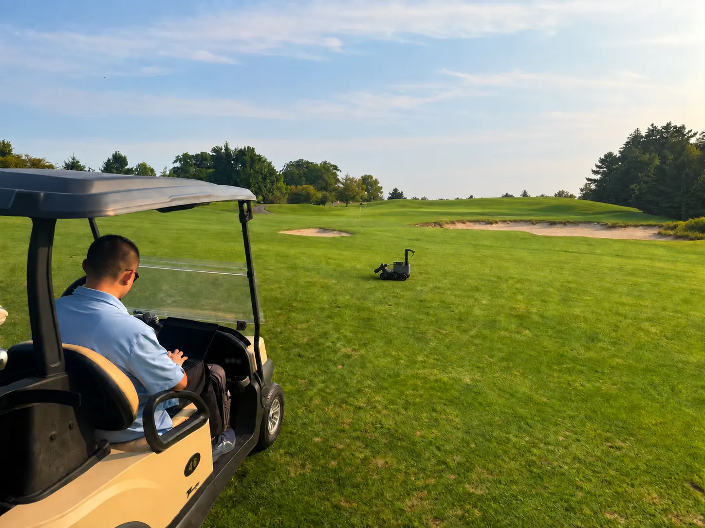 A person in a golf cart watching Divotron Vision during field testing on a fairway